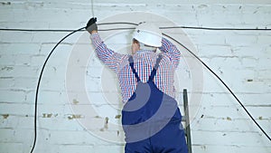 A communications engineer spins an optical cable from a large wooden cable drum.