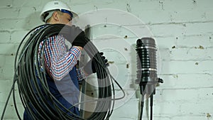 A communications engineer spins an optical cable from a large wooden cable drum.