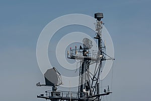 Communications tower on naval frigate against clear blue sky