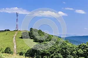 Communications tower on top of a hill complete with various antennas