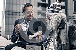 Communicative kind man talking to grey-haired senior homeless