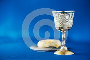 Communion still life. Unleavened bread, chalice of wine, silver kiddush wine cup on blue background. Christian communion concept