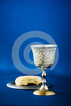 Communion still life. Unleavened bread, chalice of wine, silver kiddush wine cup on blue background. Christian communion concept