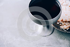 Communion still life. Unleavened bread, chalice of wine, silver kiddush wine cup on grey background. Christian communion concept photo