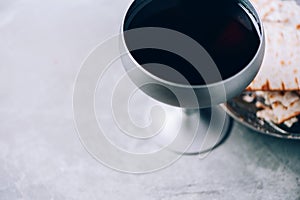 Communion still life. Unleavened bread, chalice of wine, silver kiddush wine cup on grey background. Christian communion concept