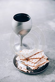 Communion still life. Unleavened bread, chalice of wine, silver kiddush wine cup on grey background. Christian communion concept