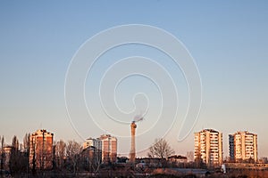 Communist housing buildings facing a polluting chimney smoking & an abandoned factory in Pancevo, Serbia.