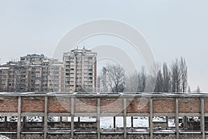 Communist housing buildings in front of an abandoned warehouse in Pancevo, Serbia, during a cold afternoon under the snow.