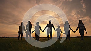 Community big family in the park. Large group of lifestyle sunset people holding hands walking silhouette nature in the