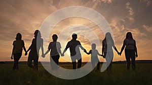 community big family in the park. large group sunset of lifestyle people holding hands walking silhouette nature in the