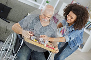 Community nurse with old disabled man on wheelchair