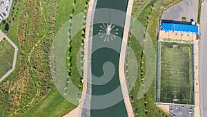 Community sports grounds for team games in football, in a park with a pond, aerial view