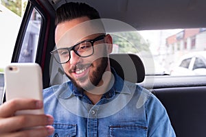 Commuter student man with glasses on smartphone using app texting message in back seat of car. Concept of commute, connection, as