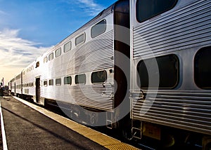 Commuter train diminishes into sunset after dropping off passengers.