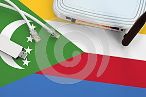 Comoros flag depicted on table with internet rj45 cable, wireless usb wifi adapter and router. Internet connection concept