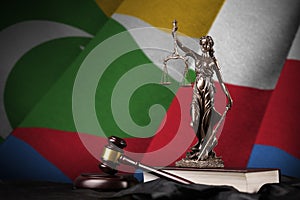 Comoros flag with statue of lady justice, constitution and judge hammer on black drapery. Concept of judgement and guilt photo