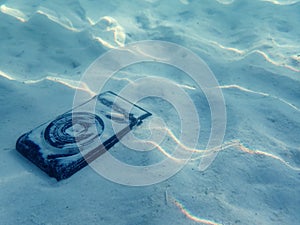 Compact camera on the sand under the sea water.