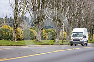 Small compact commercial transportation mini van driving on the straight local road