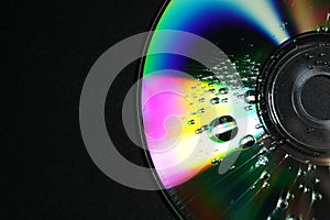 Compact disc with drops on black background, top view. Space for text