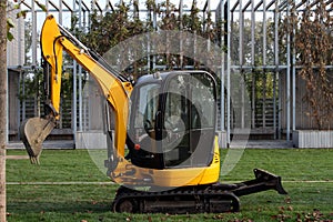 Compact excavator stands on a grassy lawn