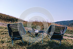 Compact folding chairs and a table, lightweight materials. Equipment for camping, tourism, active recreation. Summer sunny day.