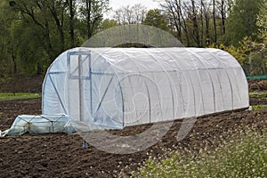 Small garden greenhouse on freshly tilled soil photo