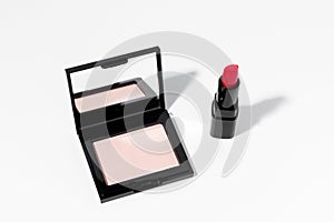 Compact mirror matte face powder, and red women's lipstick on white isolated background.