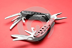 Compact portable multitool on red background, closeup