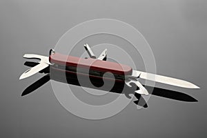 Compact portable red multitool on grey table, closeup