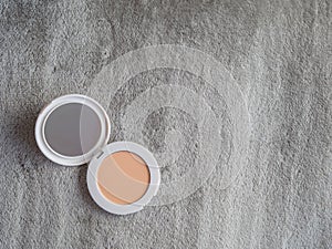 Compact powder and mirror makeup on textured background