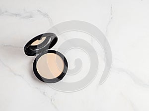 Compact powder on white marble, copy space