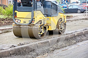 The compact road roller ramps the pavement foundation along the concrete curb and driveway