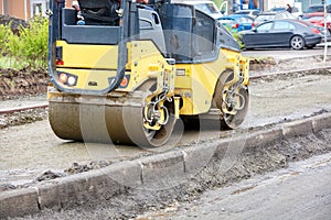 The compact road roller ramps the pavement foundation along the concrete curb and driveway photo