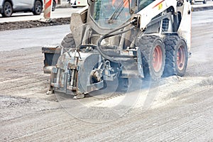Compact road tractor with hydraulic attachment cuts cracks when repairing road foundations