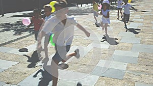 Company of active kids are jogning together on the summer city street
