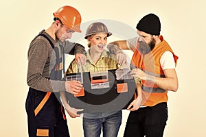 Company of cheerful workers, builder, repairer, plasterer. Strong woman concept. Woman holds toolbox, man looking in