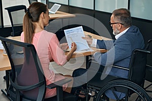 Company employees, woman and man in wheelchair, work with documents