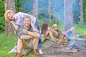 Company friends couples or families enjoy relaxing together forest. Friends relaxing near campfire after day hiking or