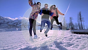 Company of friends having fun on holiday in the winter mountains. One guy and two girls enjoy the winter at the ski