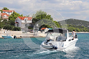 The company of friends on a small motor yacht sails along the coast near a small Mediterranean town. Rest on the water in the