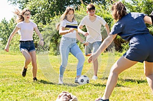 Company of glad teenagers playing football