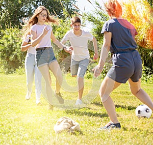 Company of glad teenagers playing football