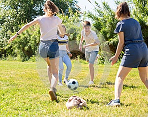 Company of glad teenagers playing football