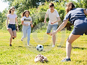 Company of glad teenagers playing football