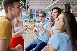 A company of good-looking friends laughing, drinking yellow cocktails and socialising at the bar in the nice summer cafe