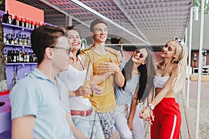 A company of good-looking friends laughing and drinking yellow cocktails, socialising at the bar in the nice summer cafe