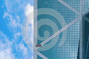 A company group of people, workers or washers, cleaning windows glass on a high rise office building with cable wires outside in