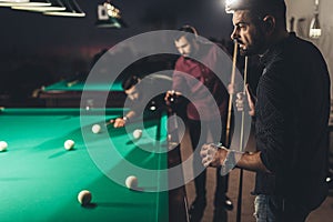 company of handsome men playing in pool