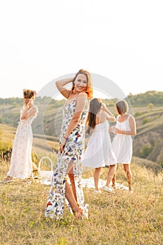 The company of happy female friends having fun and dancing outside in a picnic at hills