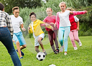 Company of kids are jogning and playing football